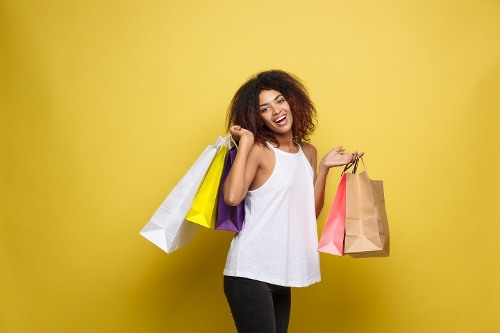 shopping-concept-close-up-portrait-young-beautiful-attractive-african-woman-smiling-joyful-with-colorful-shopping-bag-yellow-pastel-wall-background-copy-space
